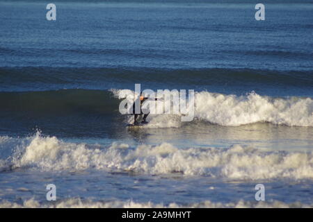 Lone Surfer Riding a Clean Wave in the Golden Light of a Winters Evening. North Sea, Aberdeen Beach, Scotland, UK. Stock Photo