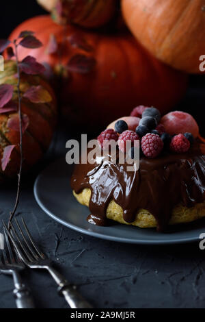 Healthy homemade dessert. Traditional steam pudding with chocolate glaze and berries and winter squashes on black background copy space Stock Photo