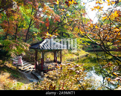 SEOUL, SOUTH KOREA - OCTOBER 31, 2019: girls in wooden Gwallamjeong Pavilion on pond in Huwon Secret Rear Garden of Changdeokgung Palace Complex in Se