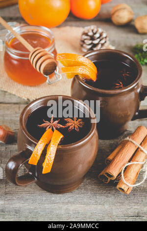 Hot mulled wine with orange, cinnamon, honey and anise on wooden background. Stock Photo