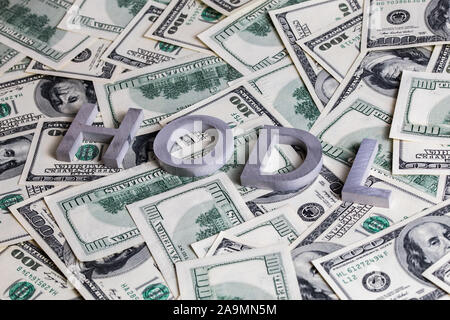 The words HODL laid with aluminium letters on the US dollar banknotes background - with selective focus. Stock Photo