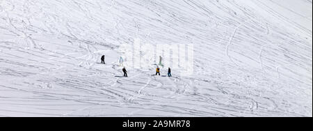 Snowboarders and skiers on snowy off piste slope at winter. Panoramic view. Stock Photo