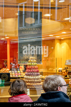 Strasbourg, France - Dec 27, 2017: Rear view of single father with daughter looking at the large tasty bakery showcase window with French macarons cake Stock Photo