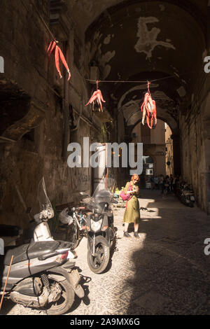 Good luck charms hanging above a narrow lane near the Pulcinella statue in Naples, Italy. Stock Photo