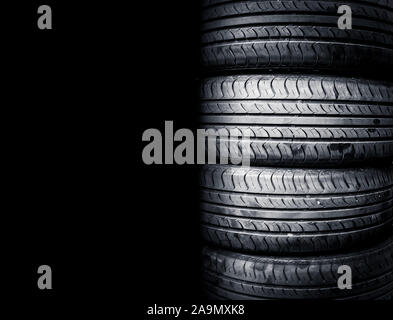 Studio shot of a set of summer car tires isolated on black background. Tire stack background. Stock Photo