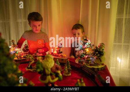 Two brothers watch model train Christmas decoration during the holiday Stock Photo