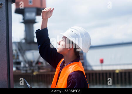 worker young male with helmet outside waving Stock Photo