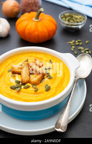 Pumpkin soup in a bowl,with fresh pumpkin seeds. Autumn foods. Healthy, vegetarian food, dark background. Stock Photo