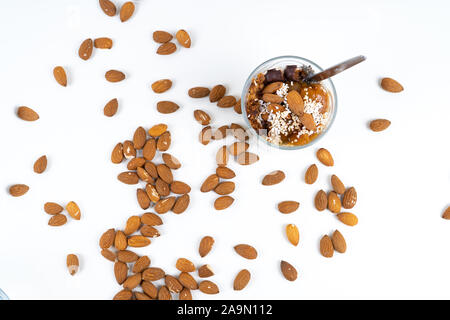 A vegan desert made of chia pudding, yoghurt, jam, fruit, cookies and almonds on white background - angled view Stock Photo