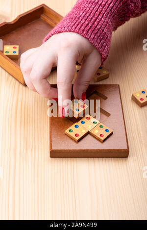 Girl is trying to assemble a mosaic puzzle. Bright manicure on fingernails. Puzzles from the category edge matching puzzle. Copy space. Puzzle concept Stock Photo