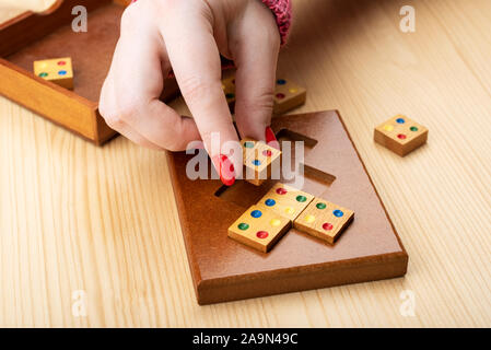 Girl is trying to assemble a mosaic puzzle. Bright manicure on fingernails. Puzzles from the category edge matching puzzle. Copy space. Puzzle concept Stock Photo