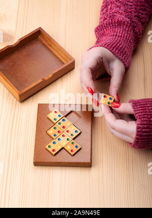 Girl is trying to assemble a mosaic puzzle. Bright manicure on fingernails. Puzzles from the category edge matching puzzle. Copy space. Puzzle concept Stock Photo