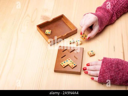 Girl is trying to assemble a mosaic puzzle. Bright manicure on fingernails. Puzzles from the category edge matching puzzle. Copy space. Puzzle concept Stock Photo