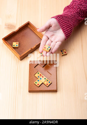 Girl is trying to assemble a mosaic puzzle. Bright manicure on fingernails. Puzzles from the category edge matching puzzle. Copy space. Puzzle concept Stock Photo