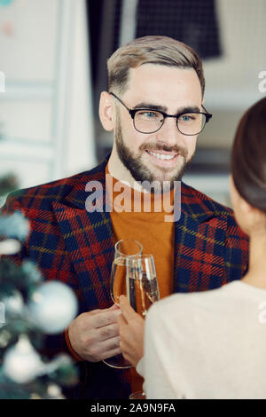 Portrait of handsome adult man smiling happily while talking to young woman and drinking champagne at elegant Christmas party Stock Photo