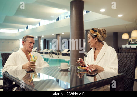 Portrait of wealthy senior couple relaxing in cafe at luxury SPA resort and eating dessert, copy space Stock Photo