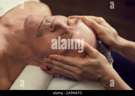 High angle close up of handsome senior man enjoying facial massage at luxury SPA center, copy space Stock Photo
