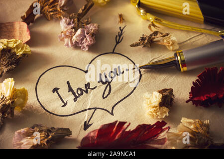 Vintage brass pen writing " I love you " in the heart and arrow image on old paper. Decoration by dry flower around it. Concept of valentine in vintag Stock Photo