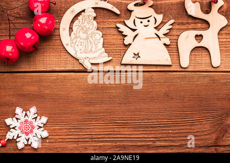 Christmas and New Year decorative wooden handmade craft toys for xmas tree: deer, angel, Santa Claus and snowflake with red small artificial apples on Stock Photo