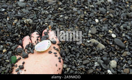 Small sea stones in a glass vessel. The idea of decorating the house with small  rocks in a jar on a wooden blurred background. Stock Photo