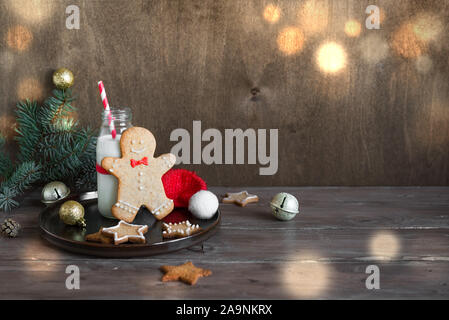 Christmas composition with Gingerbread cookies and milk on wooden background, copy space. Cookies and milk for Santa. Stock Photo