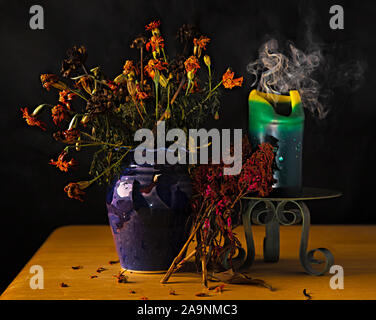 Still life with dead flowers, burnt out candle, and vase on table, all after the first frost of the year Stock Photo