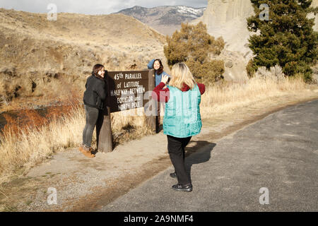 Visitors to Yellowstone National Park get their picture taken in front of the 45th Parallel Sign. Yellowstone National Park, Wyoming, USA. Stock Photo