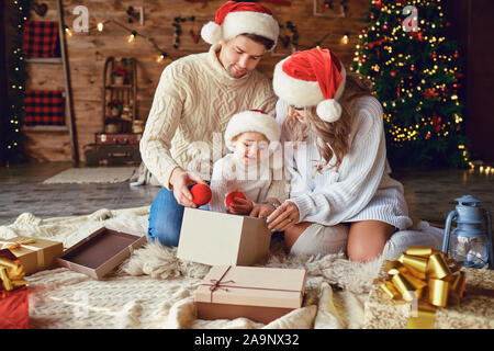 The family gives gifts to the child in the room in Christmas Stock Photo