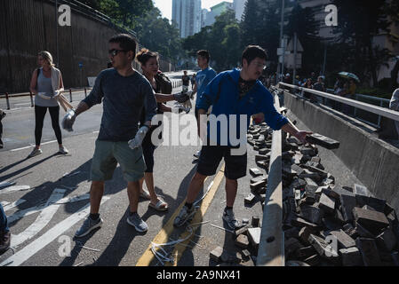 Hong Kong, China. 16th Nov, 2019. Local residents pass along road debris in an effort to clean a major roadblock set by protesters. Credit: SOPA Images Limited/Alamy Live News Stock Photo