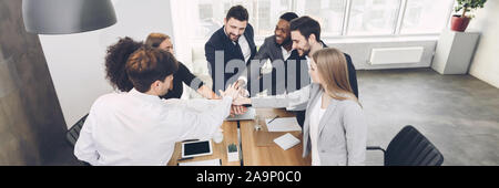 Young team joining hands involved in teambuilding activity Stock Photo