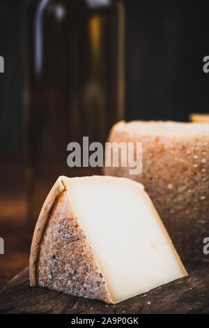 Slice of Hard Matured Cheese from Whole Cheese Wheel. Stock Photo