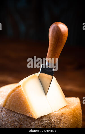 Piece Cut from Whole Matured Cheese Wheel. Traditional Food Produce. Stock Photo