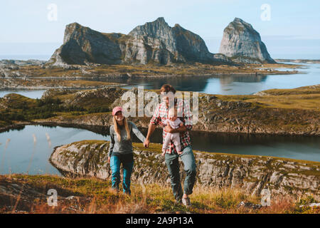 Family couple with infant baby traveling in Norway mountains vacations outdoor man and woman walking with child healthy lifestyle Helgeland islands Stock Photo