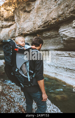 Father hiking with baby in backpack carrier travel adventure family lifestyle outdoor vacations exploring rocks canyon river Stock Photo