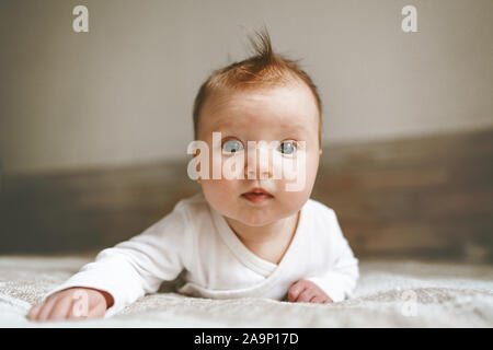 Cute baby infant crawling in bedroom adorable kid portrait family lifestyle 3 month old child close-up Stock Photo
