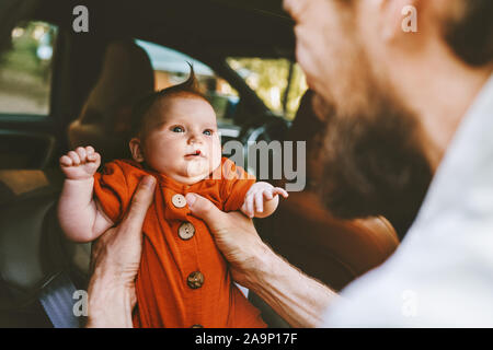 Father putting infant baby in car family lifestyle dad and child together childhood concept