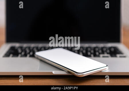 Smartphone with blank screen placed on laptop keyboard Stock Photo