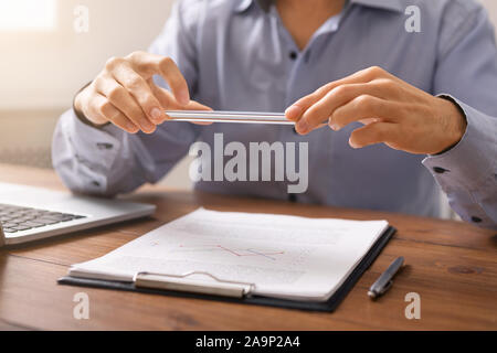 Man scanning documents in office using scanner app on smartphone Stock Photo