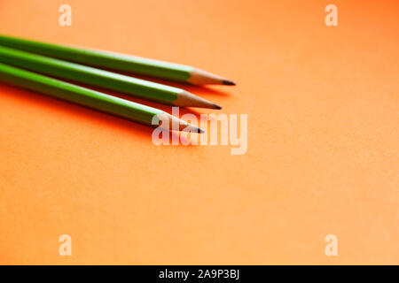 three green pencils lying on an orange background Stock Photo