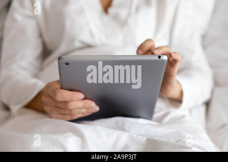 Close up view of woman using tablet computer in bed Stock Photo
