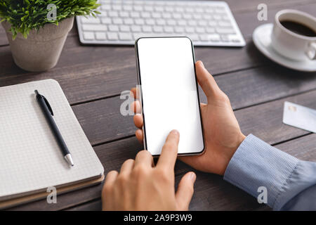 Unrecognizable man using modern smartphone with blank screen at workplace Stock Photo
