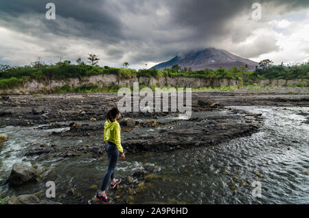 A girl adventure to the abandoned ghost town of Mount. Sinabung. The village was destroyed by natural disaster of volcano eruption. Stock Photo