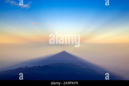 Sunrise on Teide, the tallest mountain of Spain and Atlantic Basin, view west towards  shadow of volcano cast onto the morning mist, lower levels of T