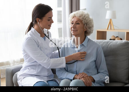 Young woman doctor holding stethoscope examining senior grandma patient Stock Photo
