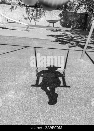 shadow of boy in cap on swing Stock Photo