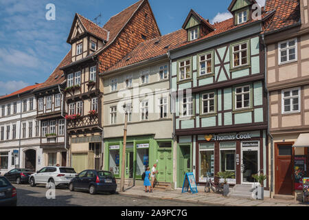 Couple of tourists in front of the оffice of a tour operator Thomas Cook in the medieval city with colorful half timbered houses Quedlinburg. Stock Photo