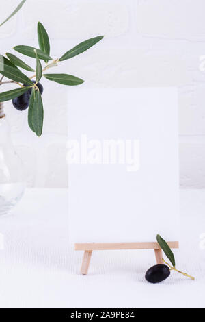 Festive wedding, birthday or business table setting and mock up invitation with olive branch on white background. Blank card mock up Stock Photo