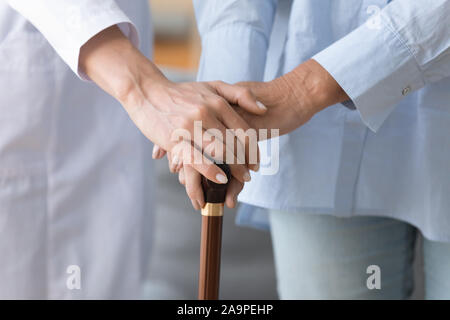 Female doctor holding old woman patient hand with cane stick Stock Photo