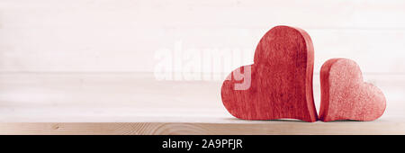 Two handmade red wooden carved hearts on light wood background couple relationship Valentine day concept Stock Photo