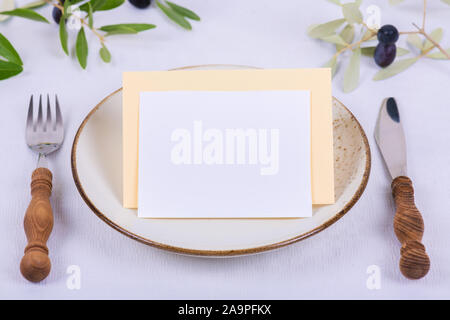 Minimalistic wedding composition with empty cards mock up for invitation, menu, place card with olive branch on white background. Cozy festive fall ta Stock Photo